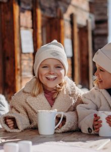 Zwei Kinder genießen warme Getränke während ihres Winterurlaubs in Großarl