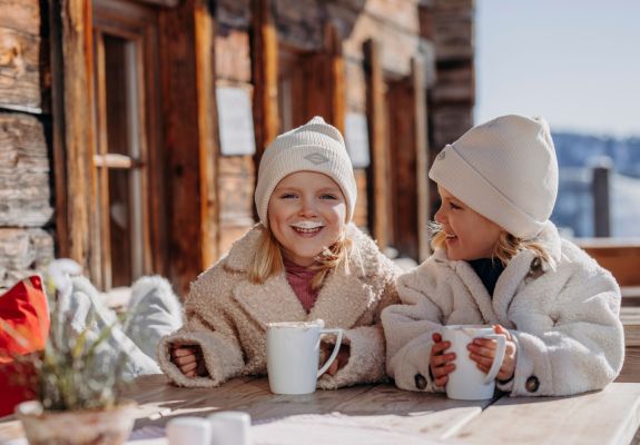 Zwei Kinder genießen warme Getränke während ihres Winterurlaubs in Großarl