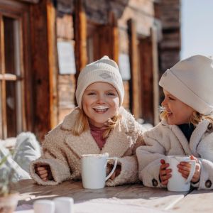 Zwei Kinder genießen warme Getränke während ihres Winterurlaubs in Großarl