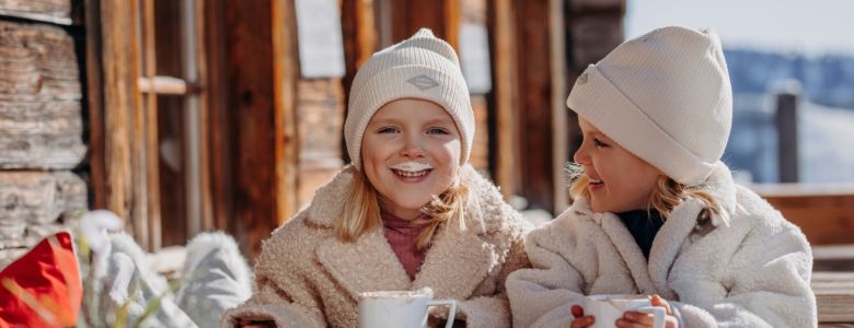 Zwei Kinder genießen warme Getränke während ihres Winterurlaubs in Großarl