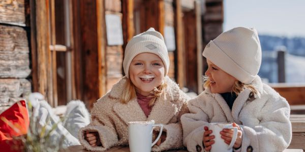 Zwei Kinder genießen warme Getränke während ihres Winterurlaubs in Großarl