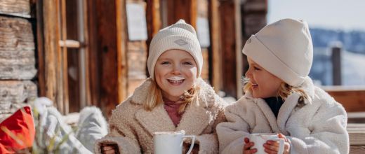Zwei Kinder genießen warme Getränke während ihres Winterurlaubs in Großarl
