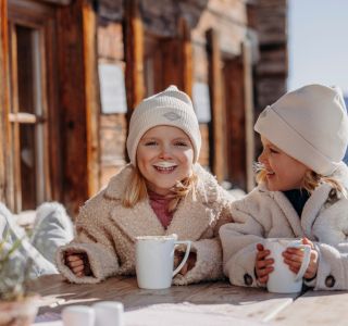 Zwei Kinder genießen warme Getränke während ihres Winterurlaubs in Großarl